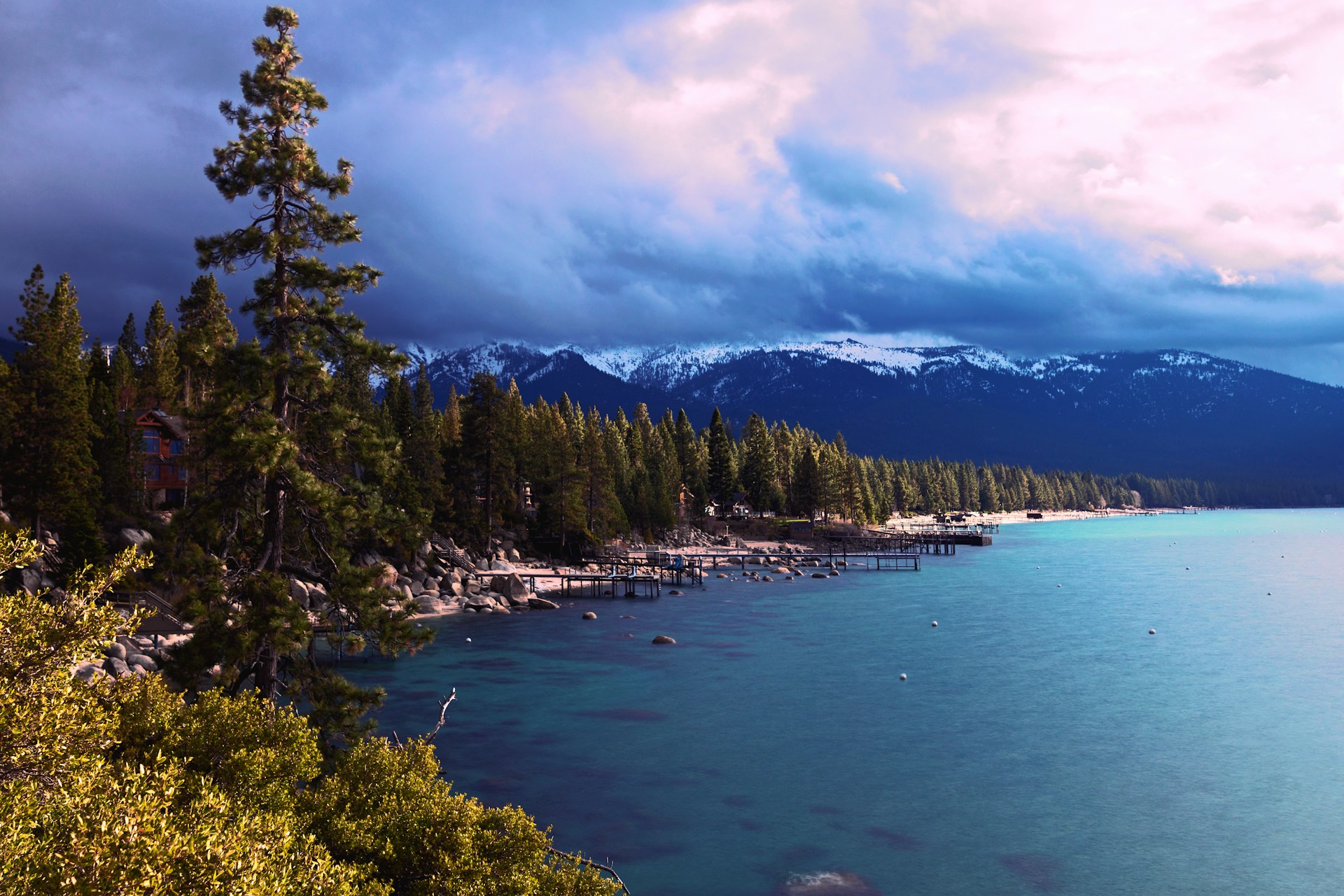 Lake Tahoe mit türkisfarbenem Wasser, Kiefernwald und schneebedeckten Sierra-Nevada-Bergen